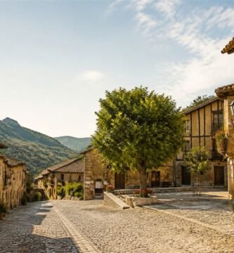Ilustración de una calle empedrada con casas tradicionales y una plaza arbolada
